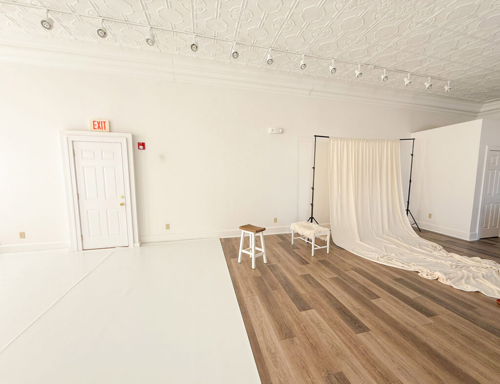 Empty photography studio with backdrop and stools.