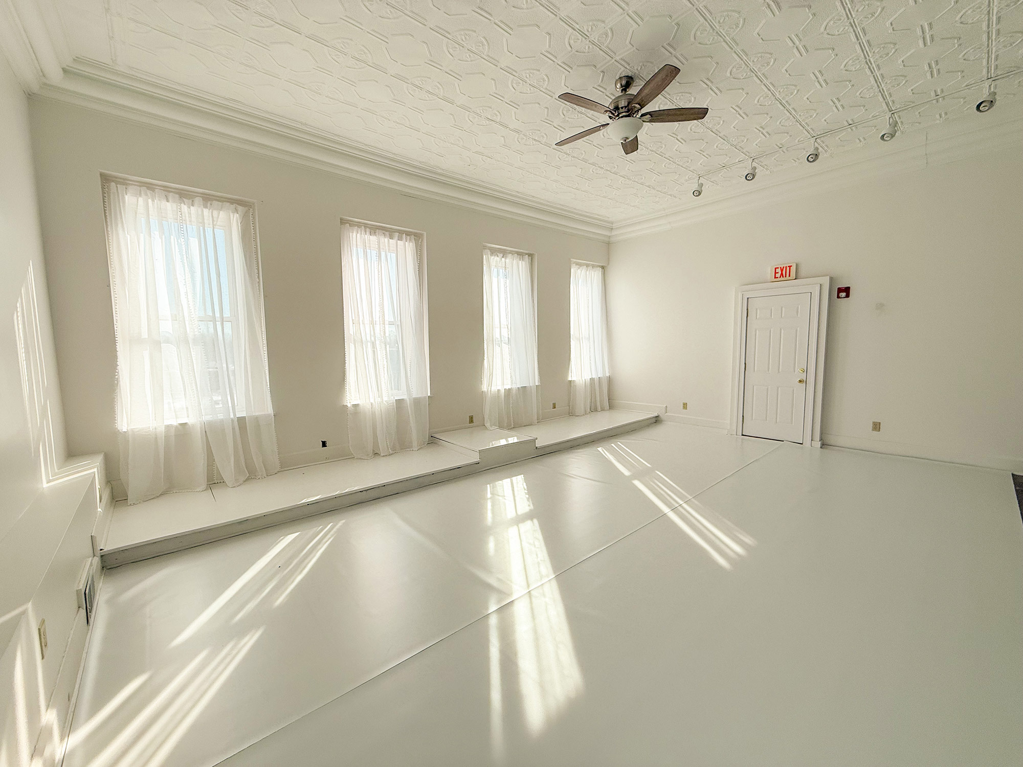 Bright empty room with large windows and white walls.